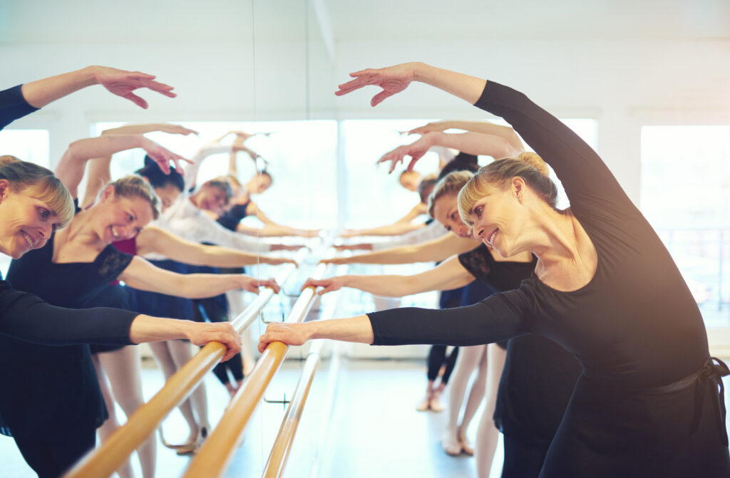 adults in ballet class stretching at the barre