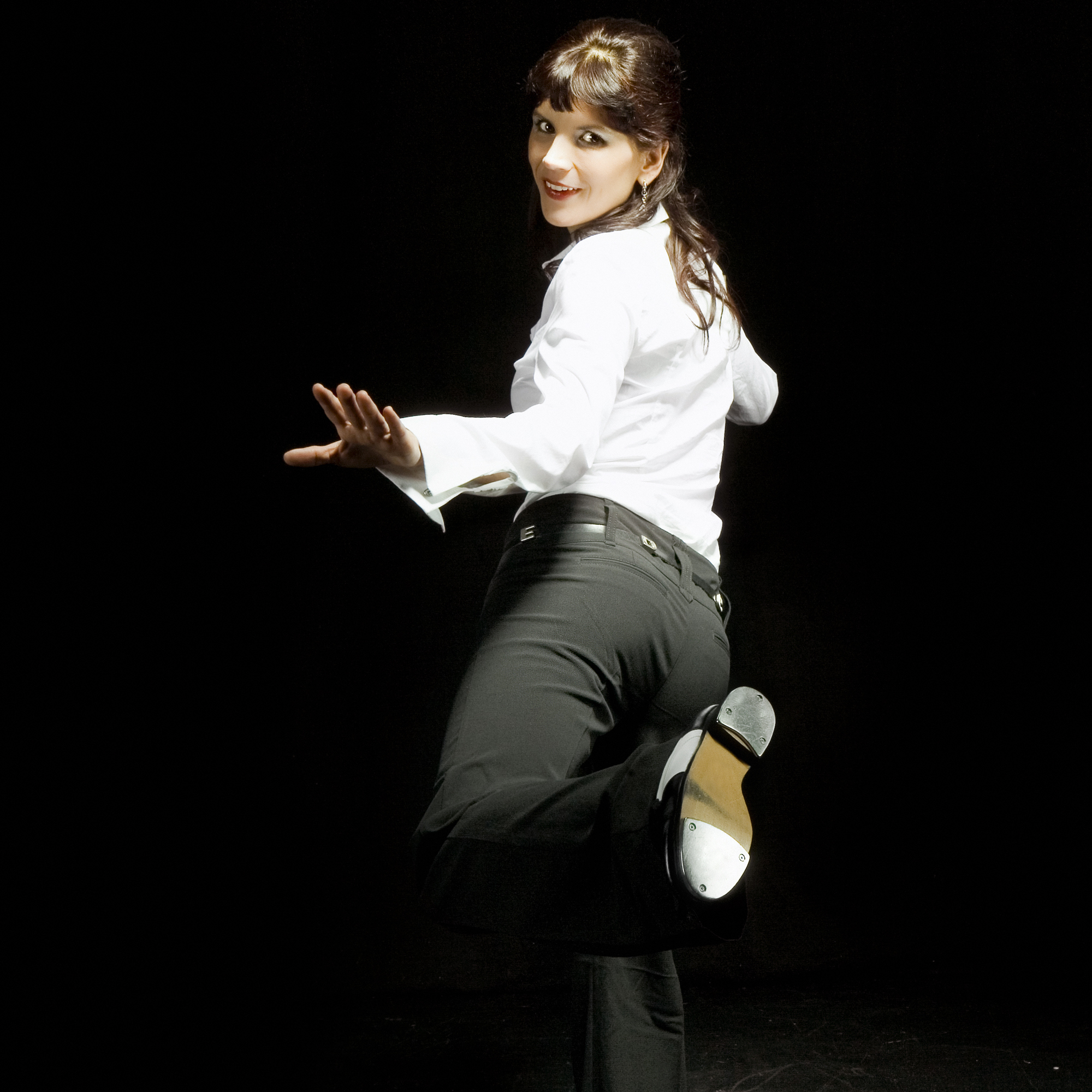 adult tap dancer showing off her tap shoes to the audience during a performanc