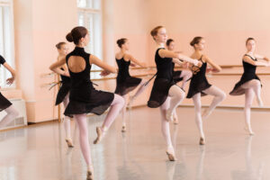 Advanced ballet dancers working on their pirouettes across the floor in ballet class