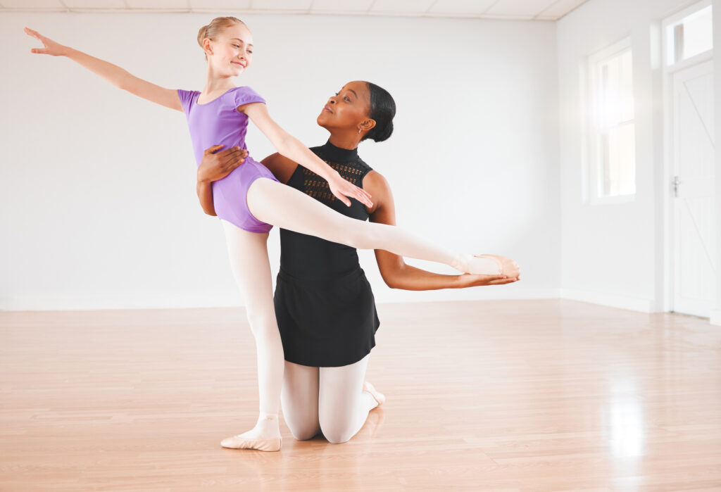 ballet teacher helping a child with their arabesque in ballet class
