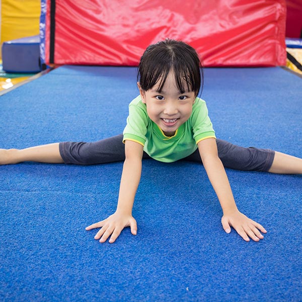 young child working on her straddle forward roll in tumbling class