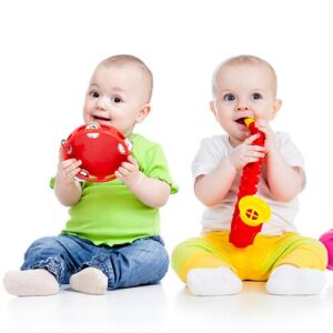 two toddlers smiling and playing with instruments during a Zumbini class