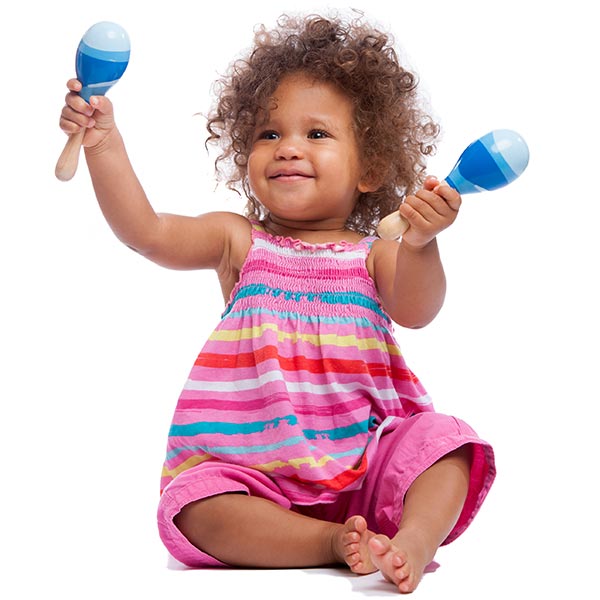 A happy biracial baby girl/ toddler waving her maracas isolated on a white background.