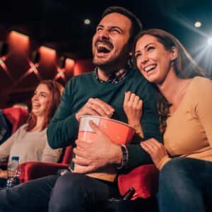 a couple at the movies laughing and eating popcorn