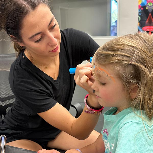 a teacher at LA Dance Academy painting a young girls face
