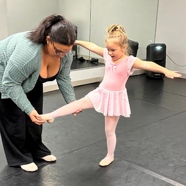young lyrical dancer working on her technique with a student assistant