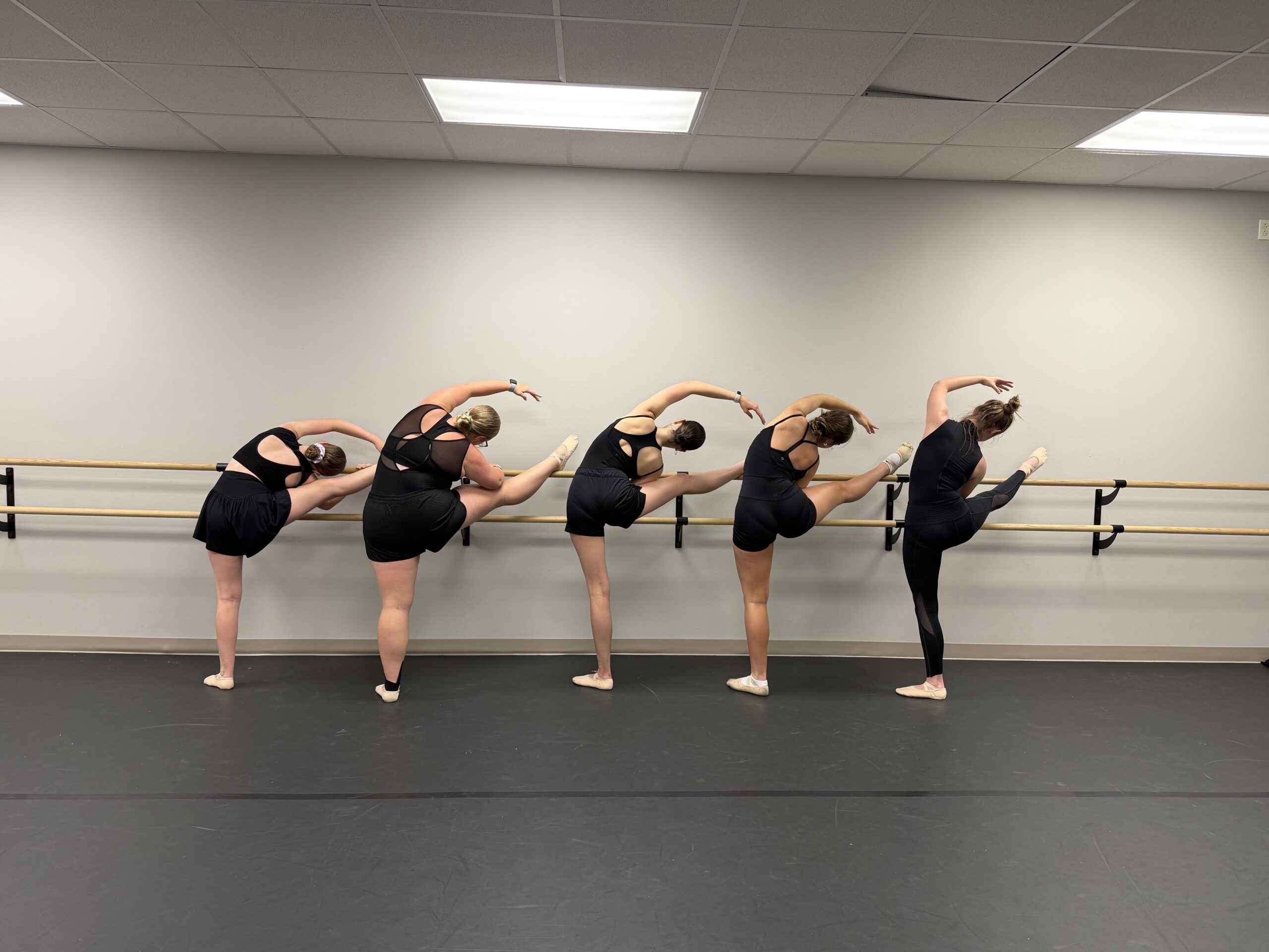 Advanced ballerinas stretching at the barre