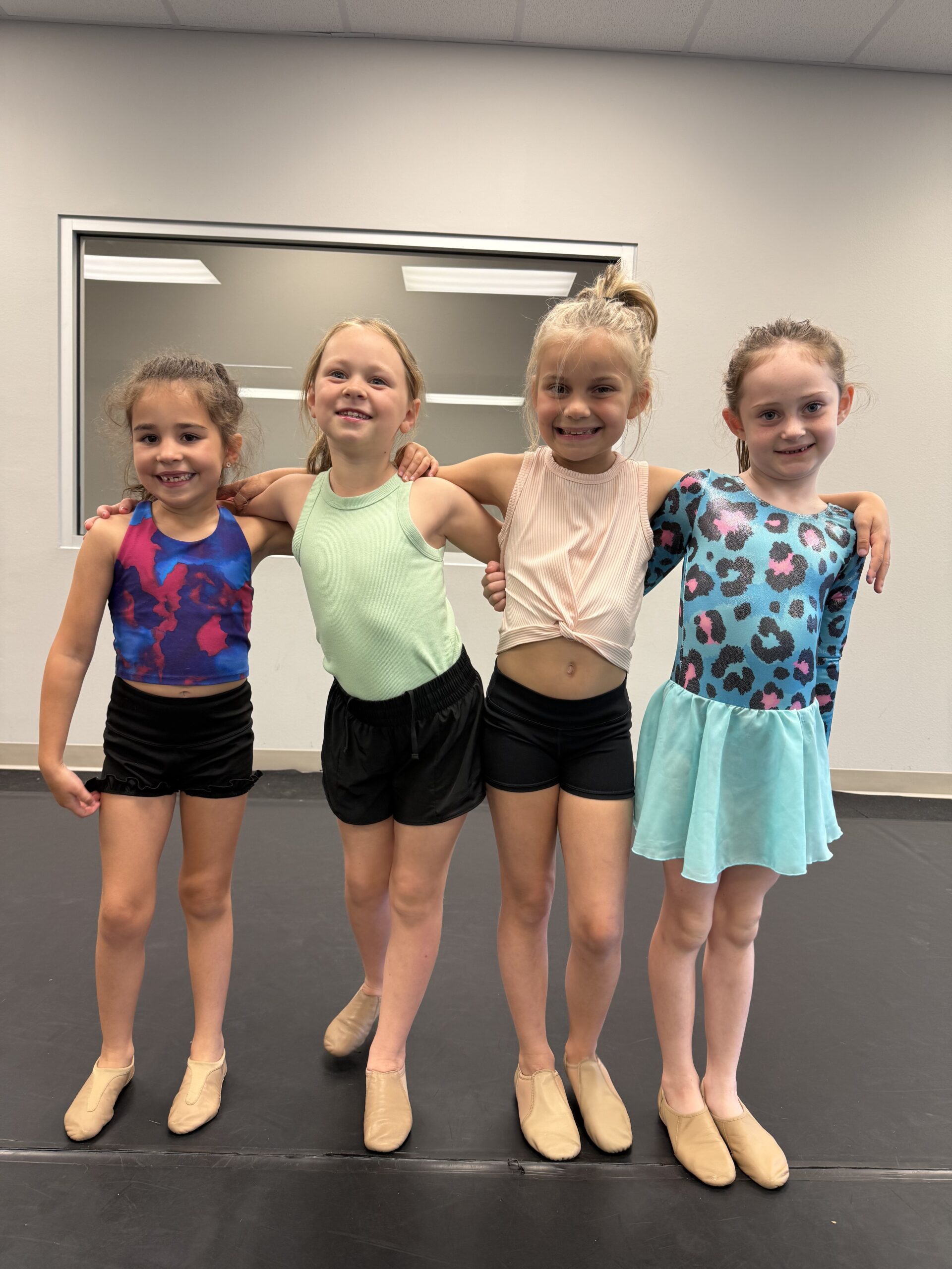 Jazz class with kids ages 6-9 smiling together after working on their recital dance.