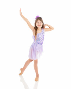 Beginner level lyrical dancer in a tendu. She is smiling with great alignment and balance.